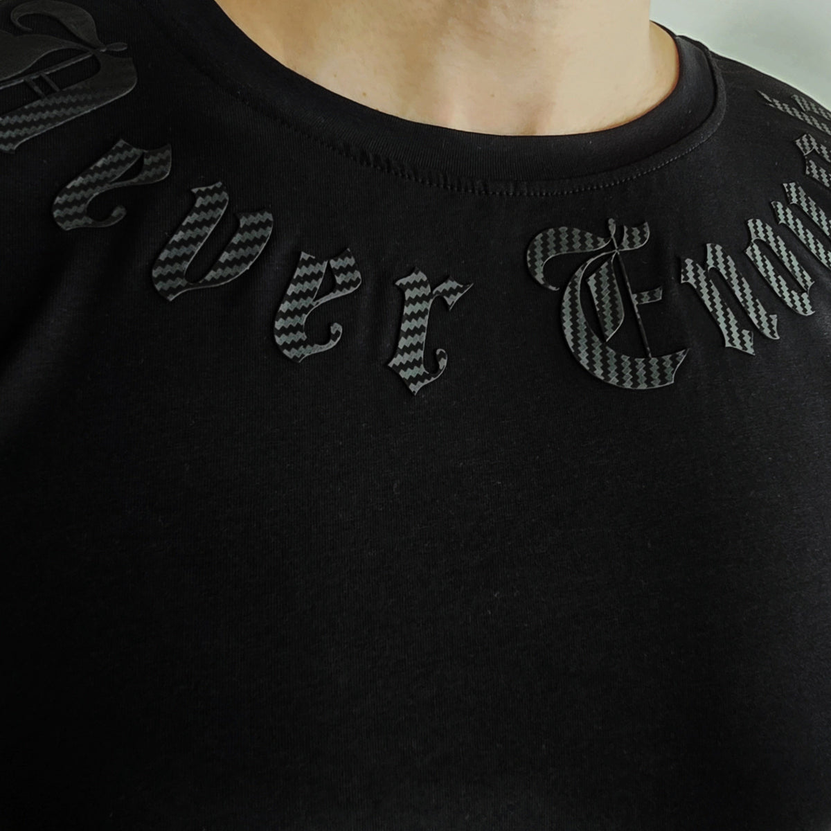 Primer plano de las letras negras Never enough alrededor del cuello de la camiseta Gold line