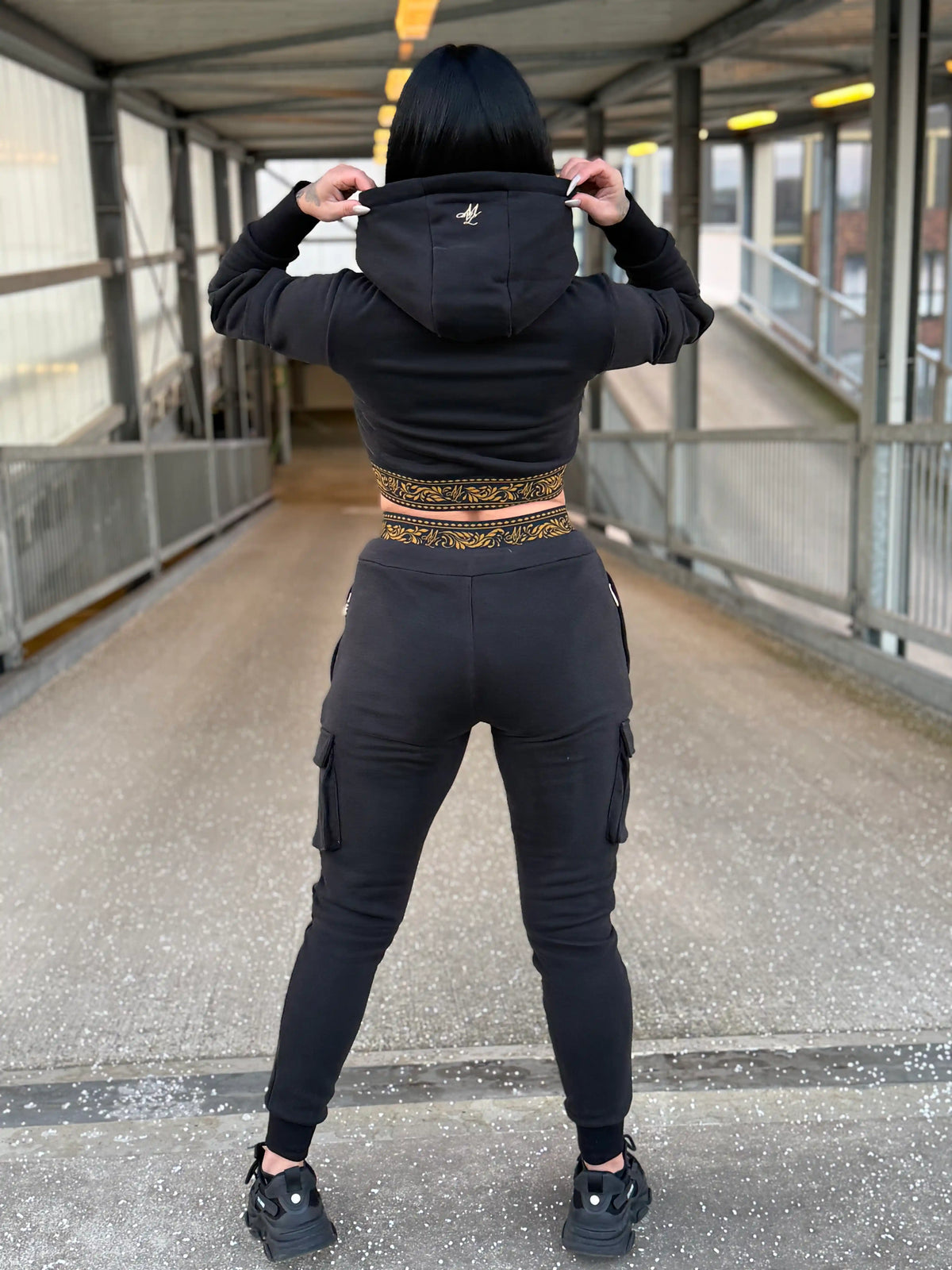 Achterkant van de cropped MVL Meander dames hoodie met capuchon op, model op een loopbrug