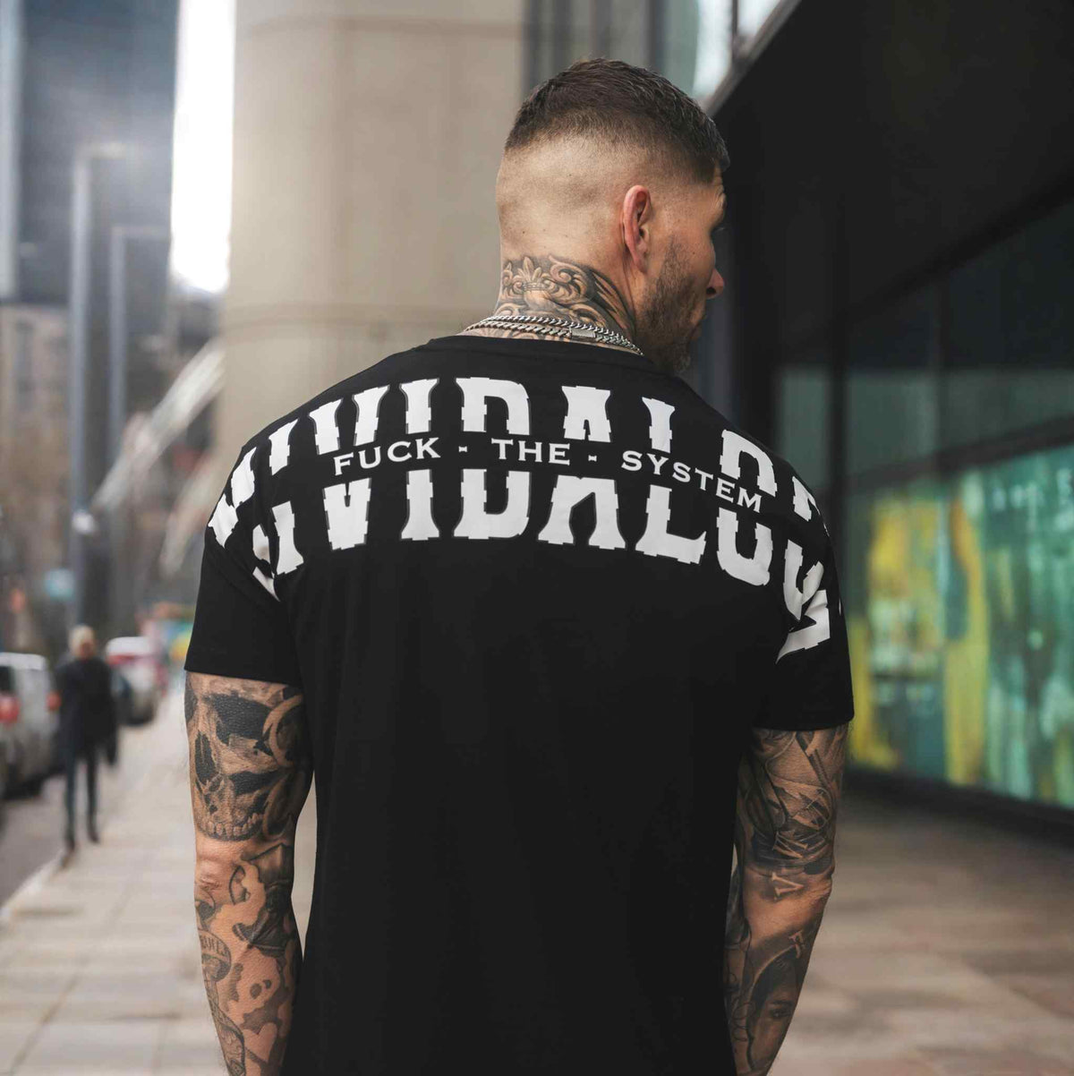 Back of the black FTS T-shirt with white Mi Vida Loca back print, worn by model on the street