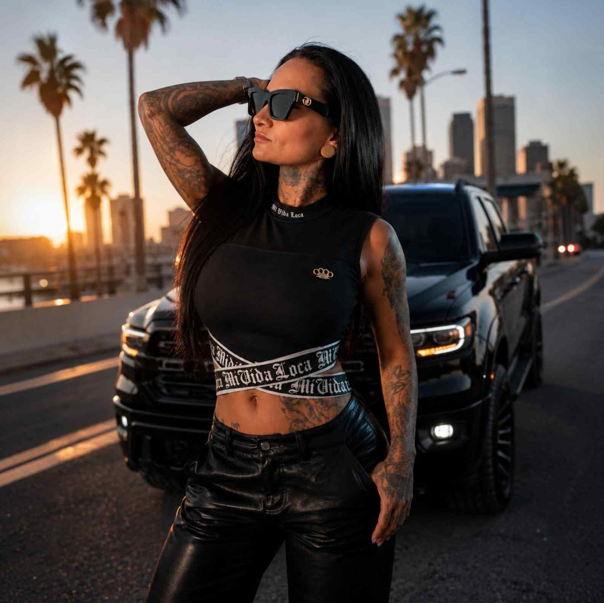 Top femme Signature noir porté par une mannequin avec lunettes de soleil au coucher du soleil entre les palmiers