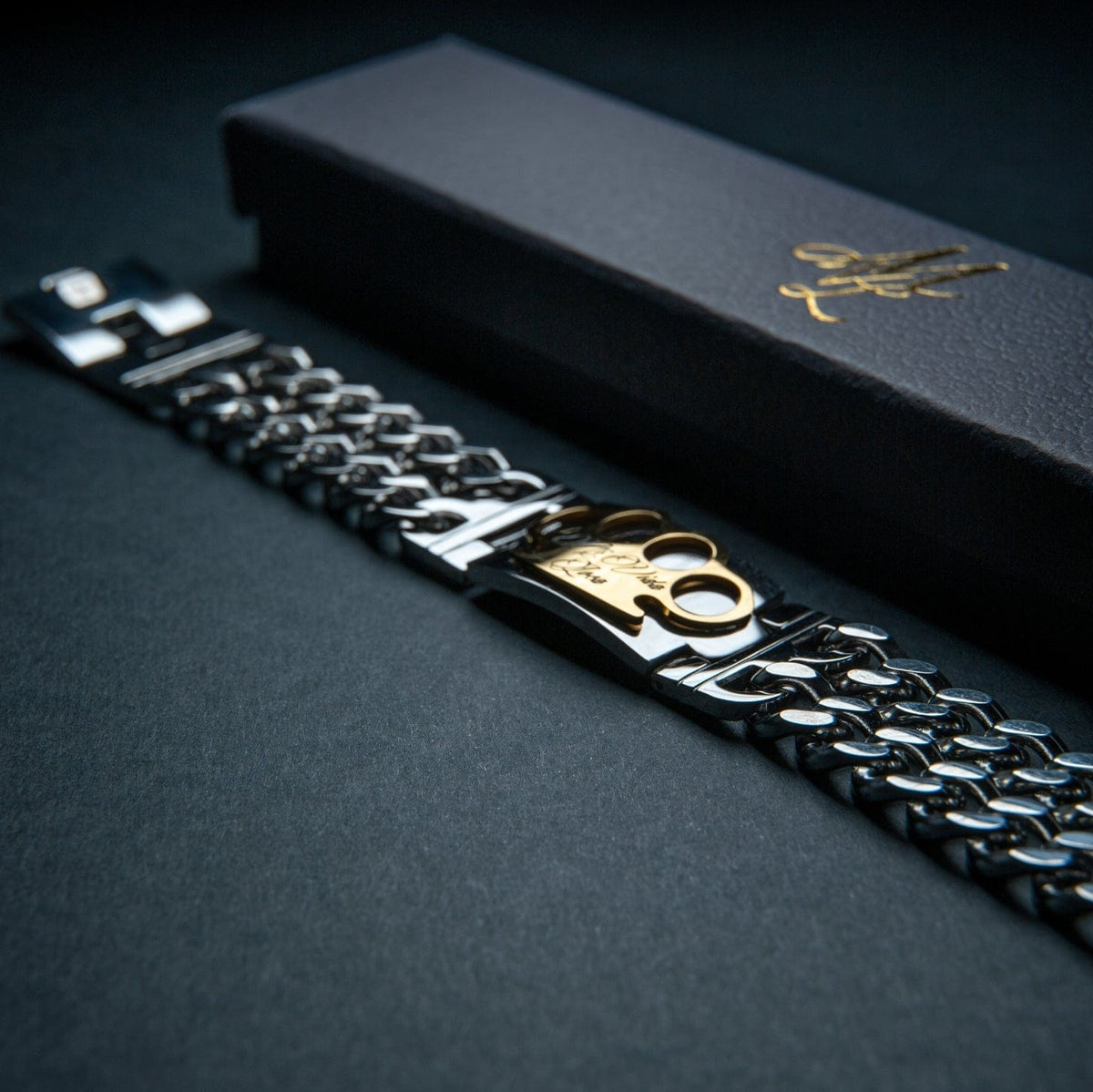 Bracelet Mi Vida Loca MVL argenté avec plaque logo MVL dorée à côté du coffret cadeau noir