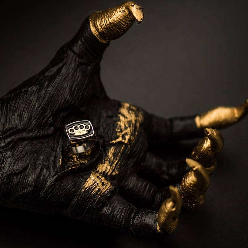 MVL zegelring zilver aan een zwart-gouden sculptuurhand, sfeerbeeld