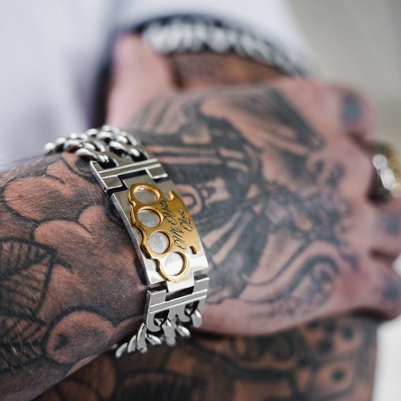 Bracelet MVL argenté avec logo MVL doré au poignet tatoué, gros plan